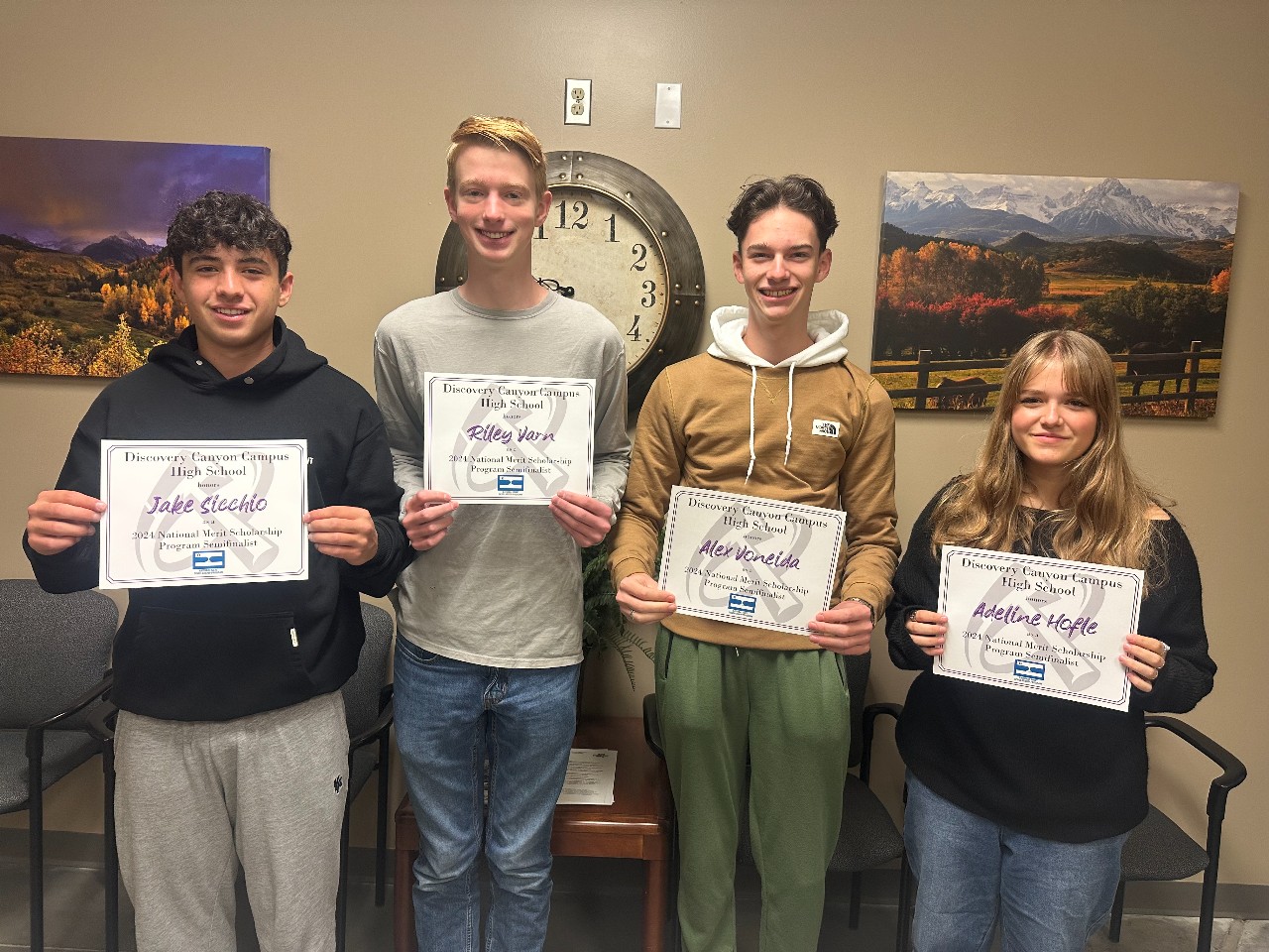 Four students smile for a picture while holding certificates
